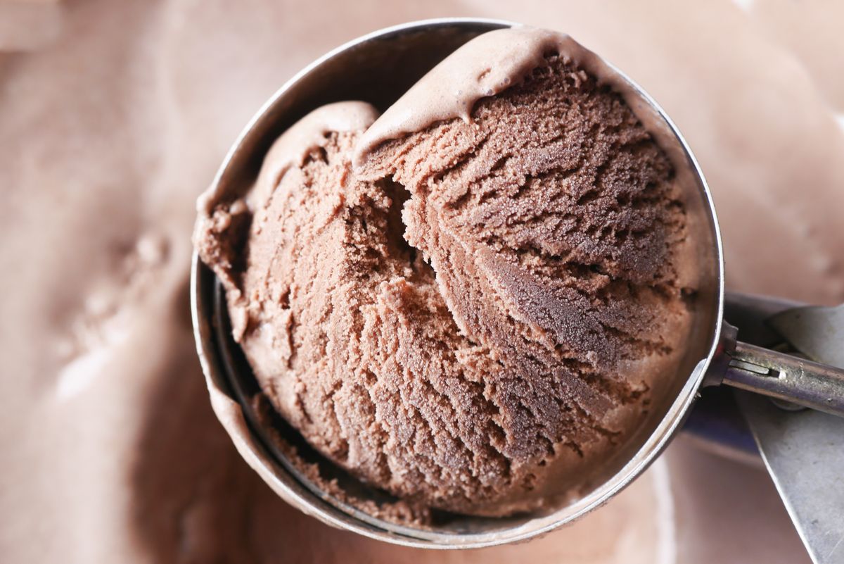 Scoop of dark chocolate ice cream lifted from a tub
