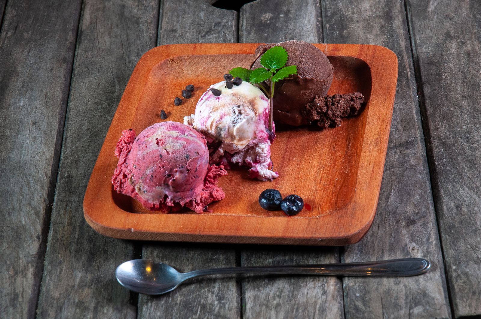 An assortment of gourmet ice cream scoops on a wooden plate
